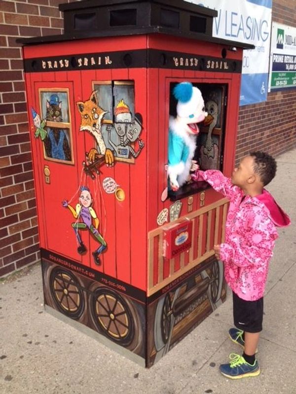 Red vintage carnival puppet booth with child in pink jacket